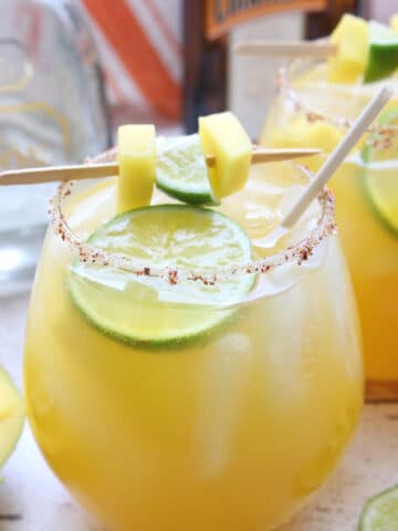 glass of mango margarita with lime and mango garnish