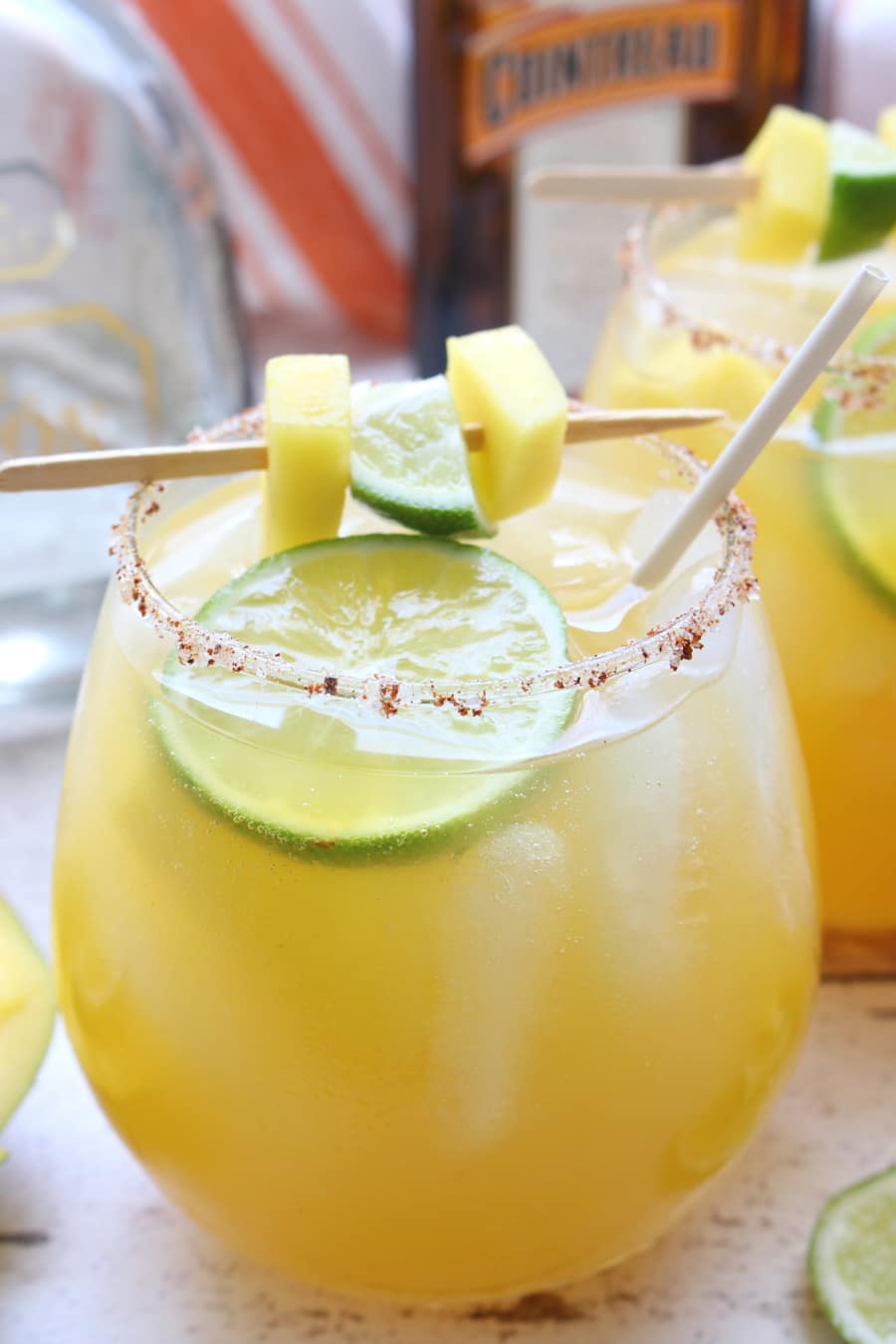 glass of mango margarita with lime and mango garnish