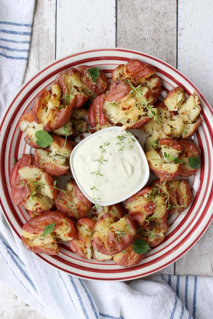 Plate of smashed potatoes with a bowl of ranch dressing in the middle