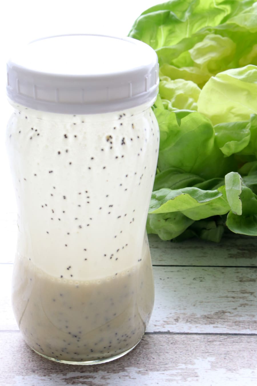 jar of salad dressing with head of lettuce in background