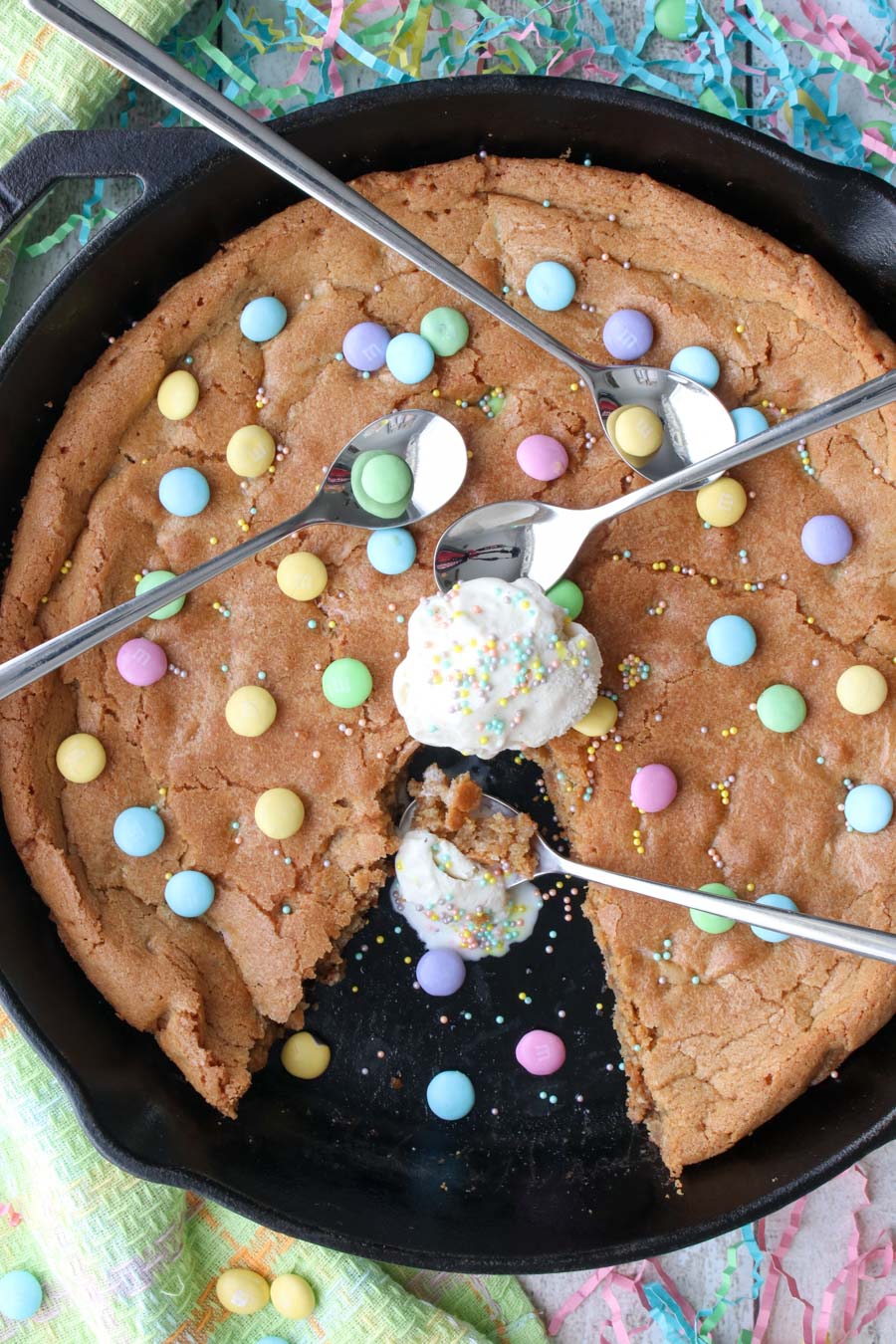 Cookie in a skillet with a scoop of ice cream on top and three spoons