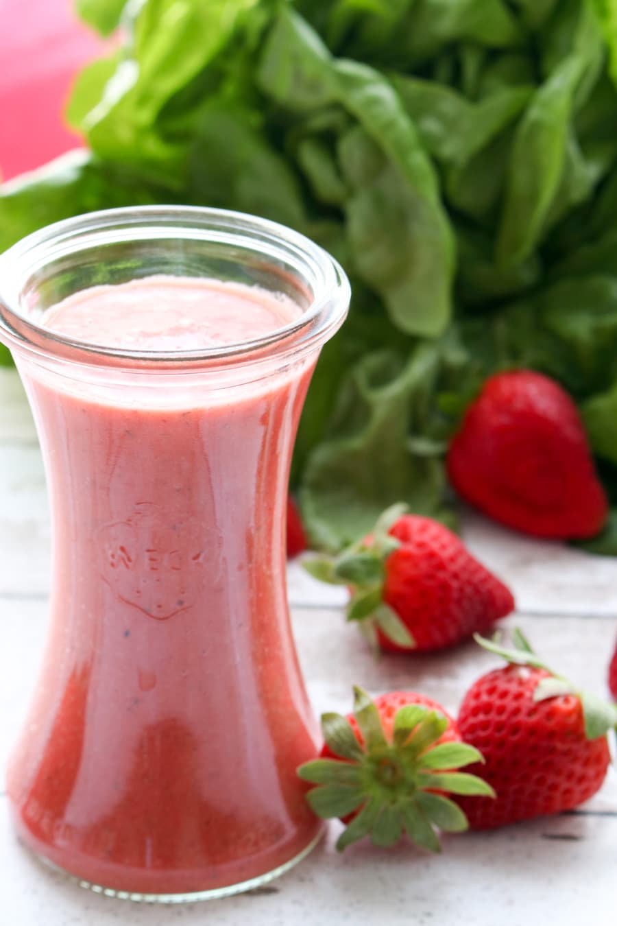 bottle of pink strawberry champagne vinaigrette salad greens with lettuce in the background