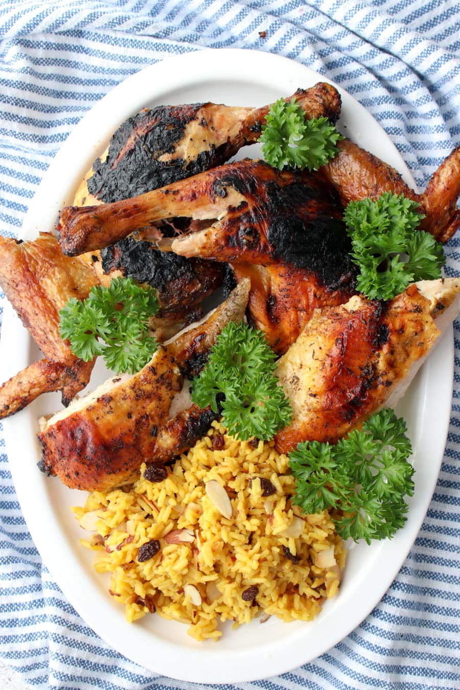 Grilled chicken and yellow rice on a white platter