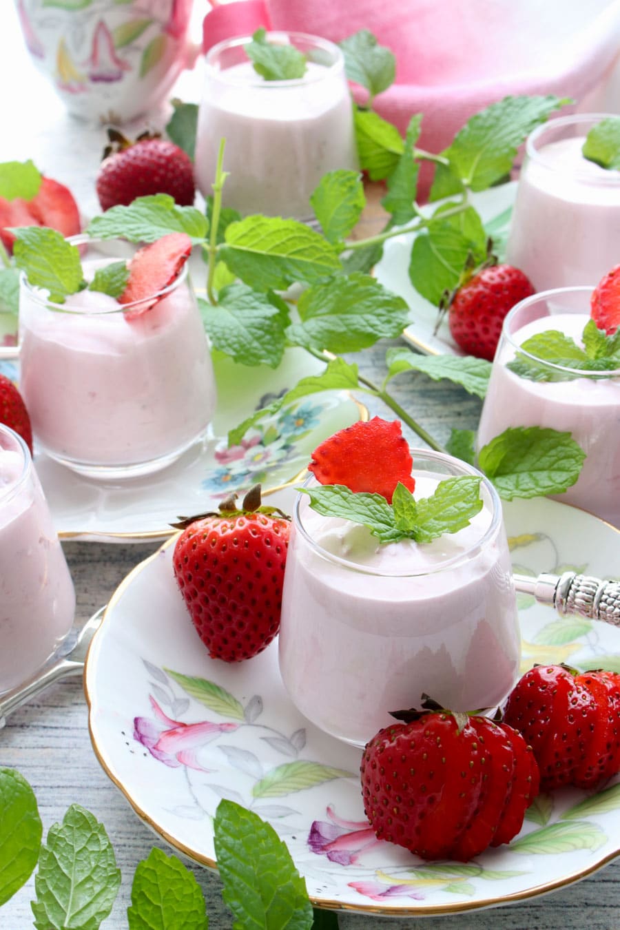 several small dishes for strawberry cheesecake mousse sitting on flowered plates