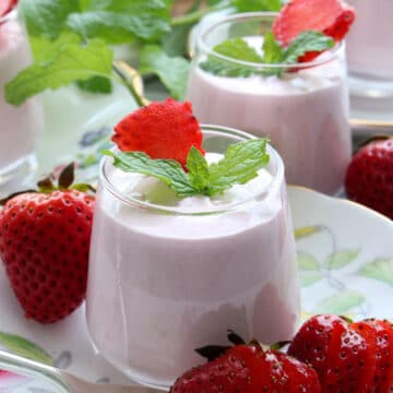 Strawberry cheesecake mousses in a small dessert jar on a flowered tea plate