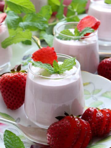 Strawberry cheesecake mousses in a small dessert jar on a flowered tea plate