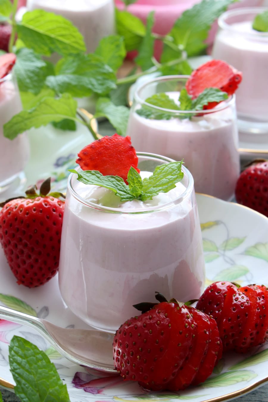 Strawberry cheesecake mousses in a small dessert jar on a flowered tea plate