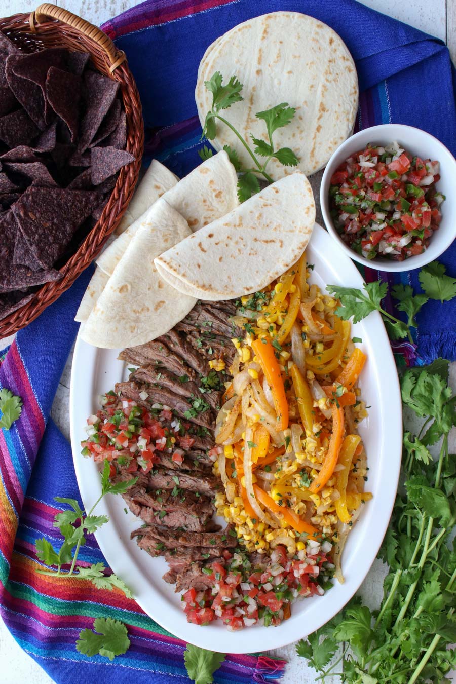 platter of beef fajita with peppers, onions, corn and soft tortillas 