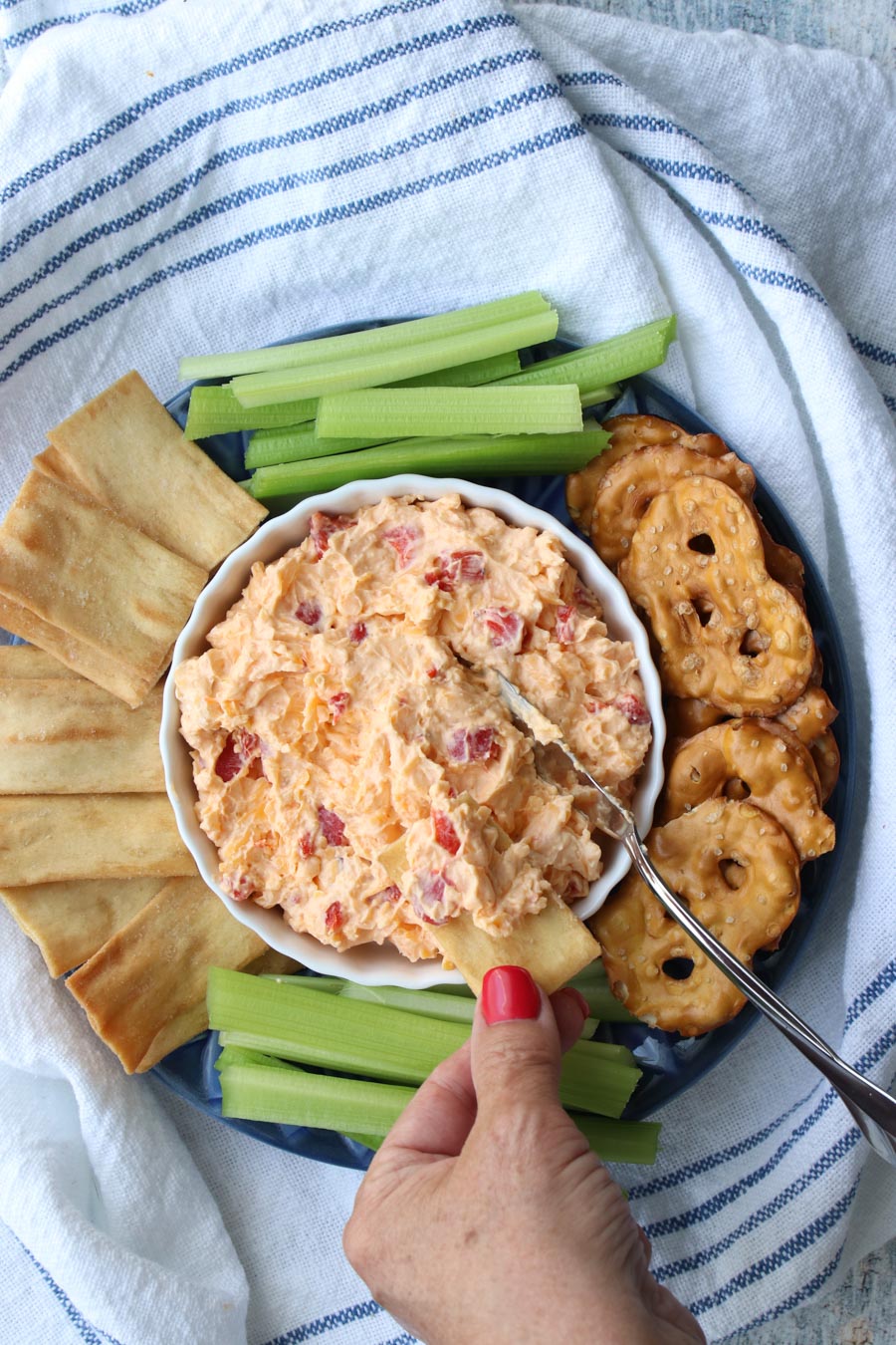 woman's hand dipping cracker into bowl of pimento cheese