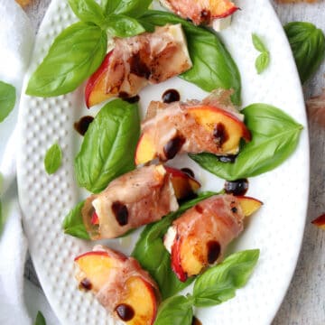 white platter of prosciutto wrapped peaches and feta cheese