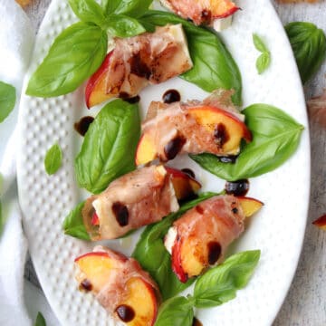 white platter of prosciutto wrapped peaches and feta cheese