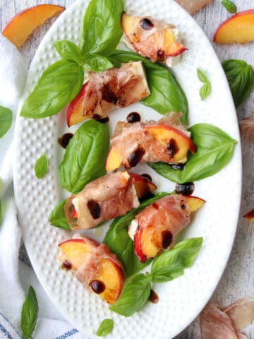 white platter of prosciutto wrapped peaches and feta cheese