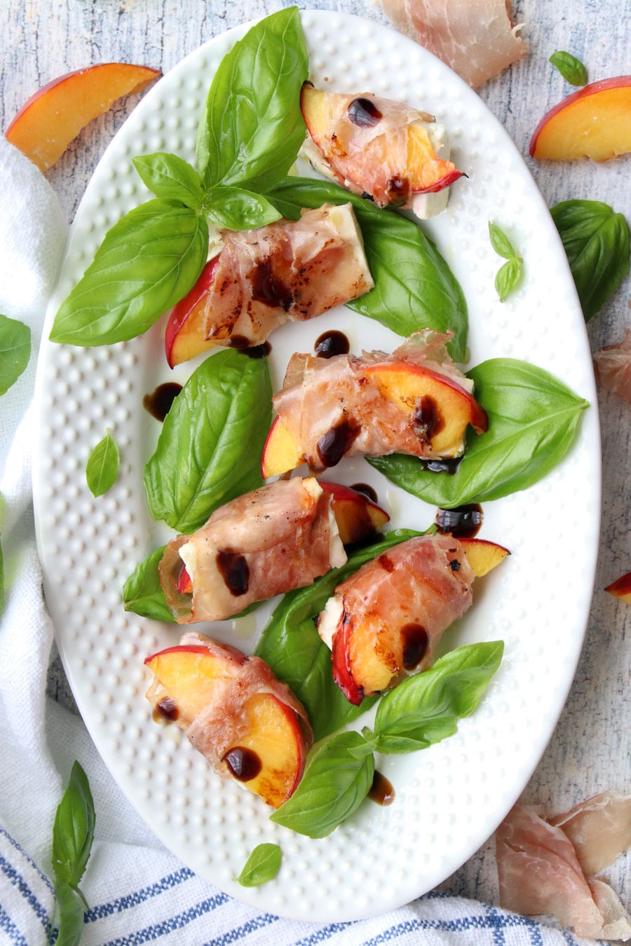 white platter of prosciutto wrapped peaches and feta cheese