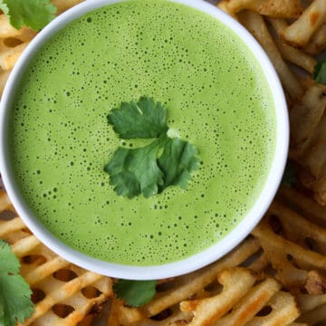 bowl of green cilantro sauce surrounded by waffle fries