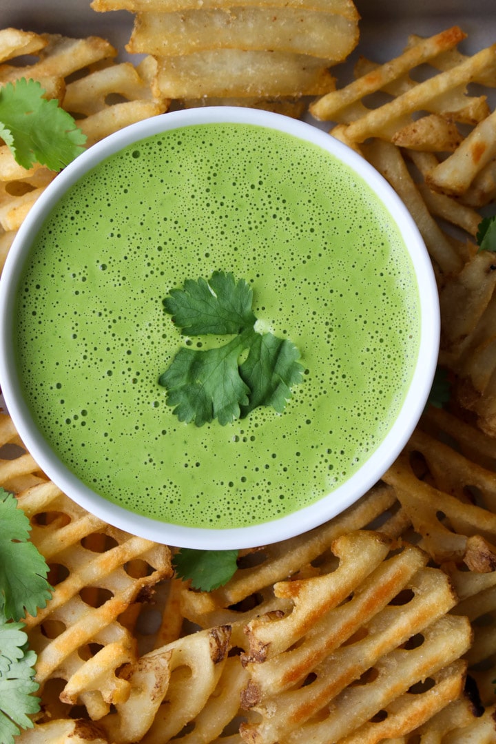 bowl of green cilantro sauce surrounded by waffle fries