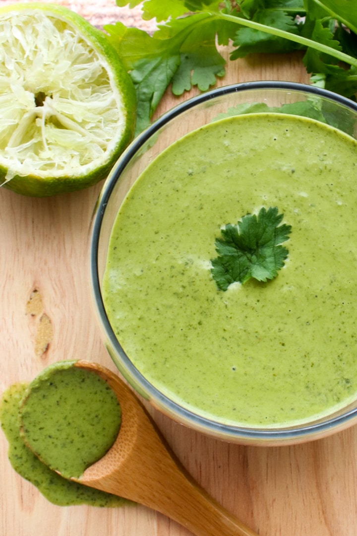 bowl of cilantro lime sauce next to a small wooden spoon of sauce