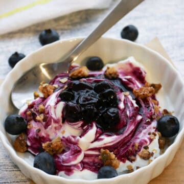 bowl of yogurt covered with blueberry sauce and granola