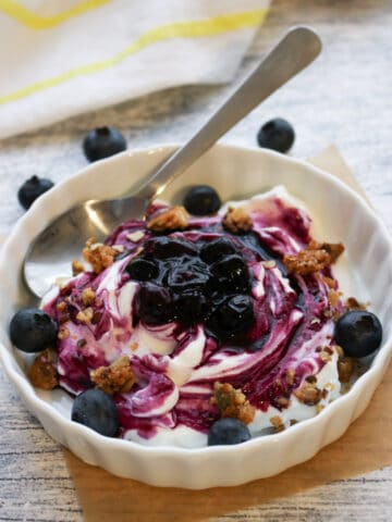 bowl of yogurt covered with blueberry sauce and granola