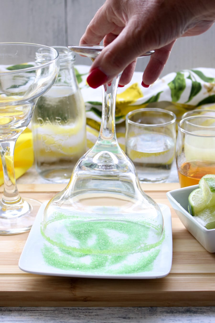 upside down margarita glass being dipped into green sugar for the rim