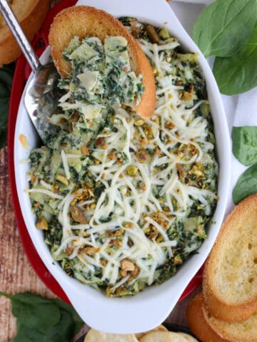 casserole dish with hot spinach dip surrounded by bread and crackers