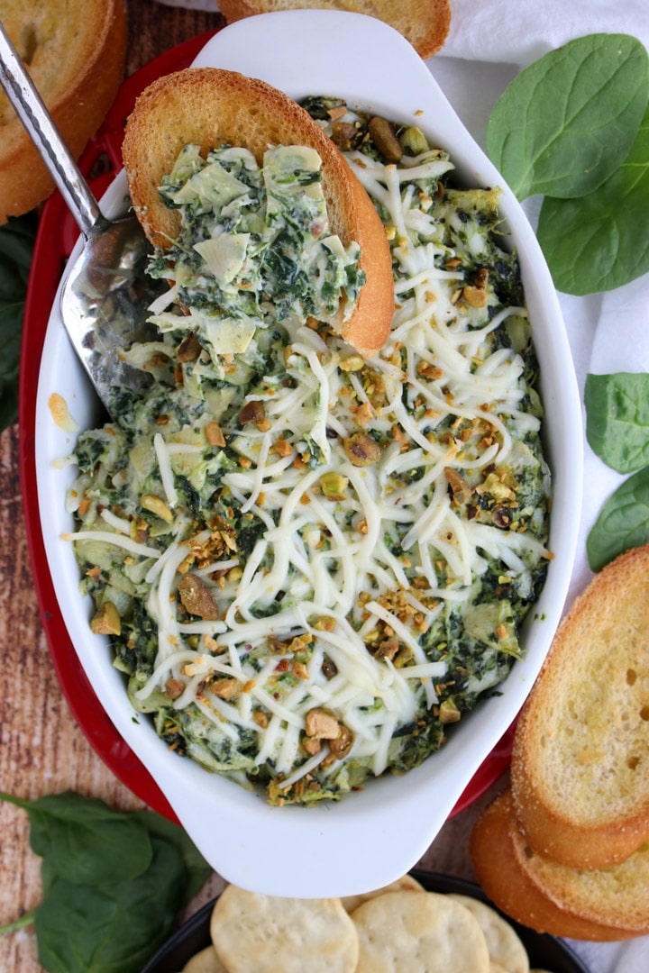 casserole dish with hot spinach dip surrounded by bread and crackers