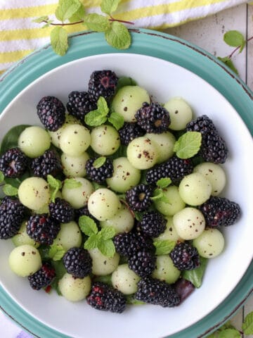 Blackberrys and melon balls in a white dish sprinkled with pepper