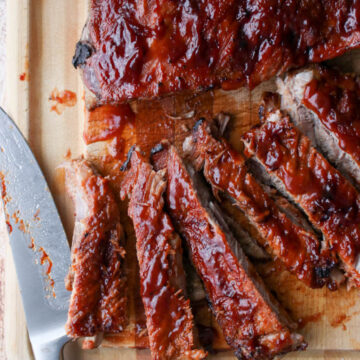 bbq ribs on a cutting board with a large knife