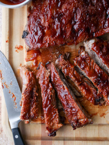 bbq ribs on a cutting board with a large knife