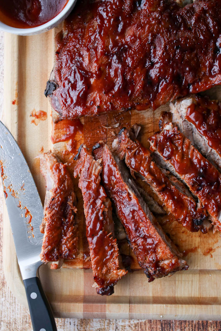 bbq ribs on a cutting board with a large knife