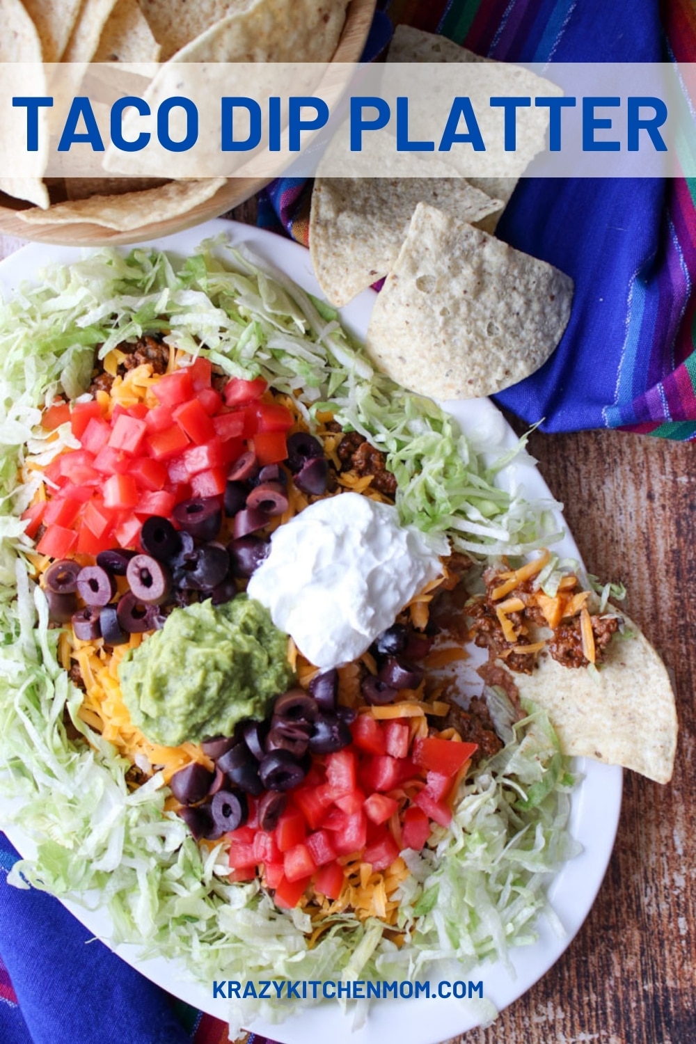 My twist on Mom's layered taco dip plated on a large platter for easy dipping. Layers of beans, taco beef, cheeses, and all the toppings. via @krazykitchenmom