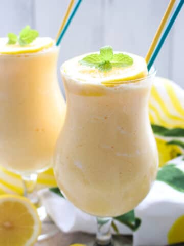 TWO GLASSES OF FROZEN LEMONADE WITH A YELLOW AND BLUE STRAW