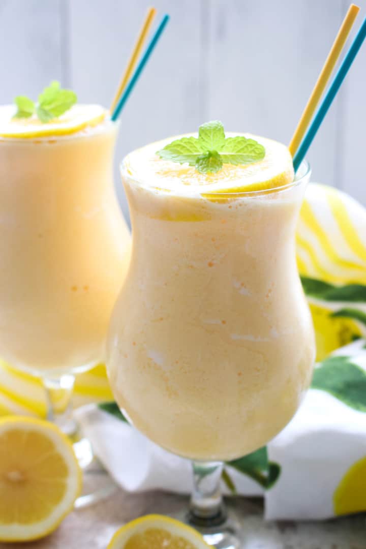 TWO GLASSES OF FROZEN LEMONADE WITH A YELLOW AND BLUE STRAW