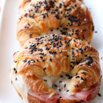 ham and cheese croissant sandwiches lined up on a white plate