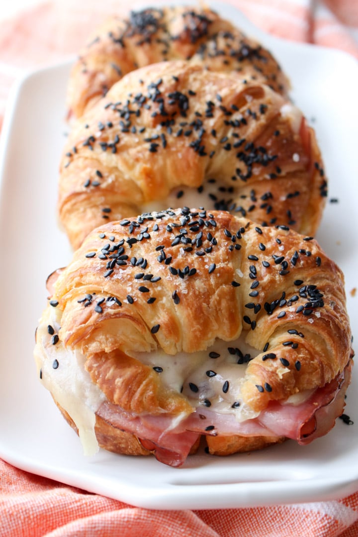 ham and cheese croissant sandwiches lined up on a white plate