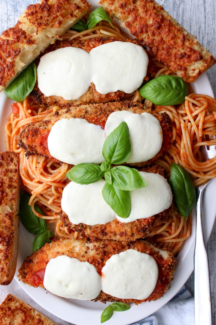 platter of spaghetti and chicken parmesan with garlic bread