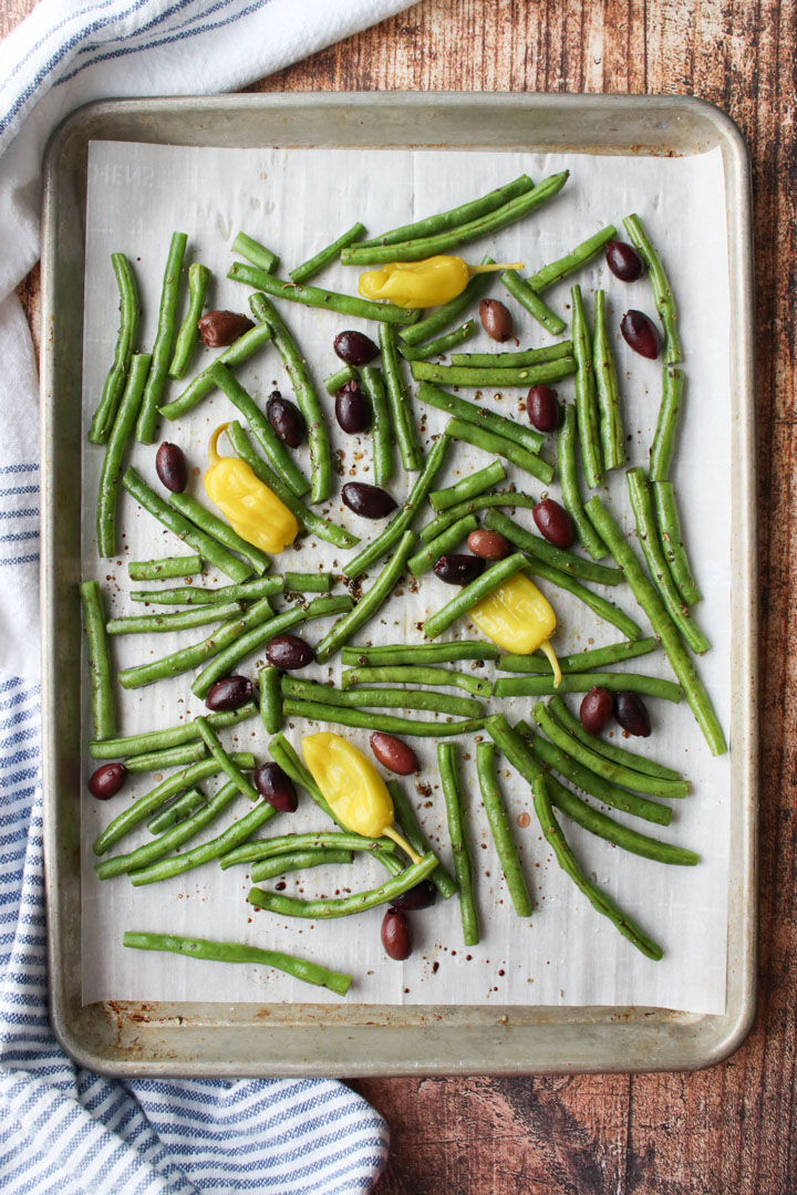 cookie sheet with green beans, olives, peperoncini peppers