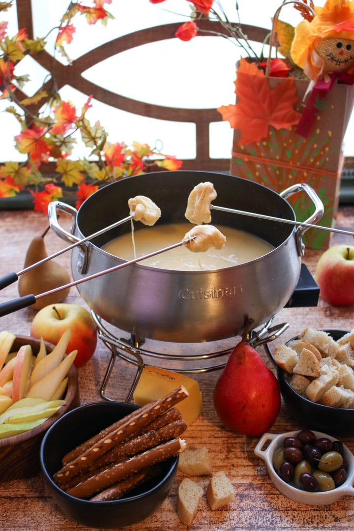 cheese fondue pot with three forks dipping into pot.