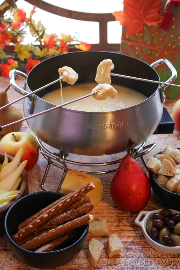 cheese fondue with three fork dipping into the pot