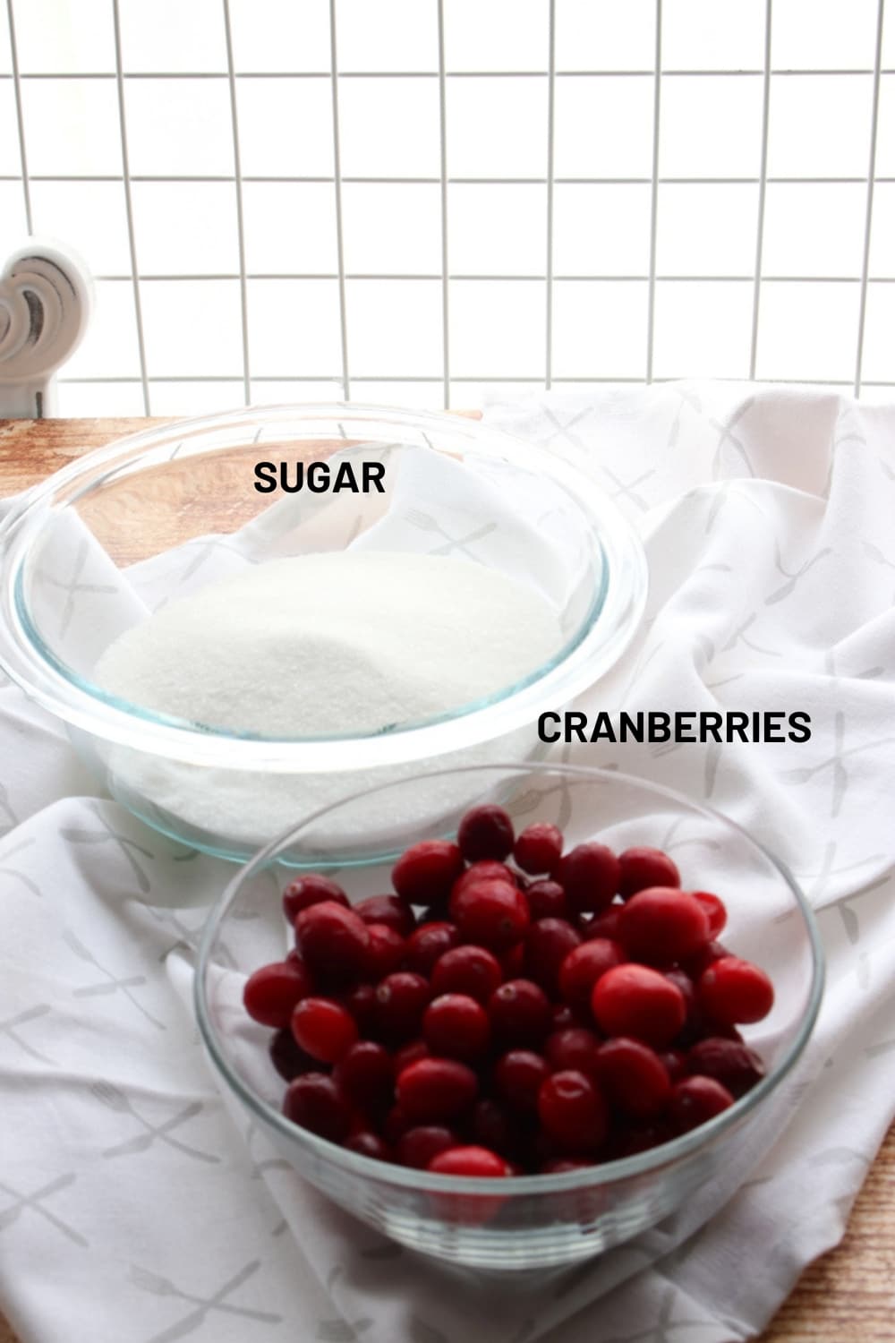 bowl of sugar and a bowl of cranberries sitting on a white cloth