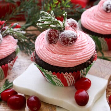 Pink Cranberry buttercream on a chocolate cupcake decorated with sugared cranberries and sugared rosemary