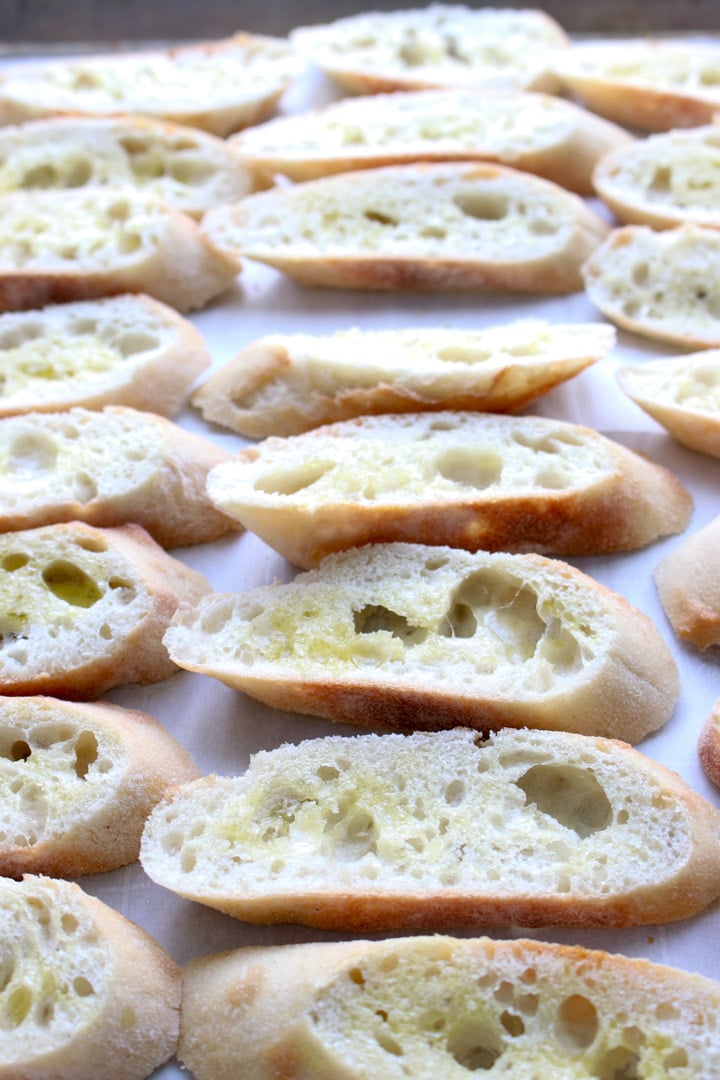 French bread slices brushed with olive oil on a cookie sheet