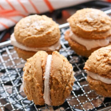 four gingerbread sandwich cookies on a baking rack. One cookie turned on it's side