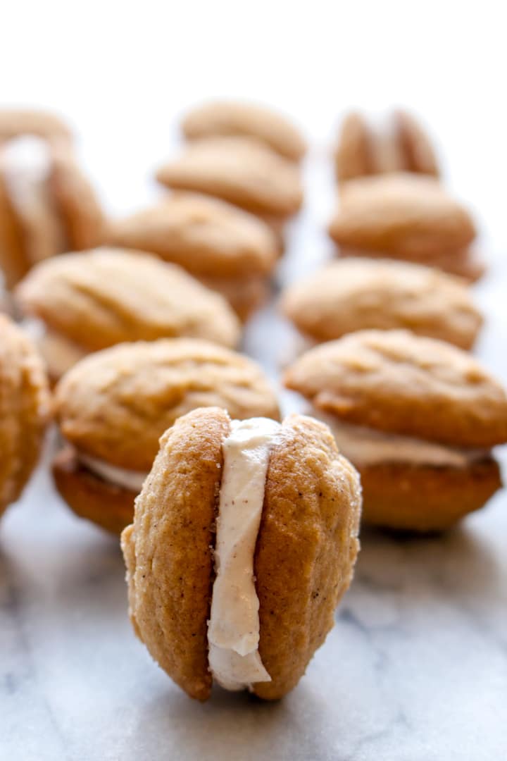 one gingerbread sandwich cookie on it's side with rows of cookies in the background