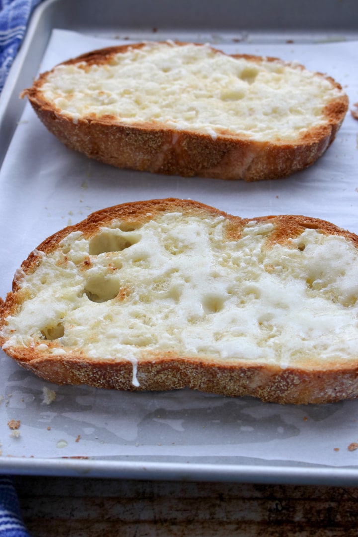 two slices of cheese toast on a cookie sheet