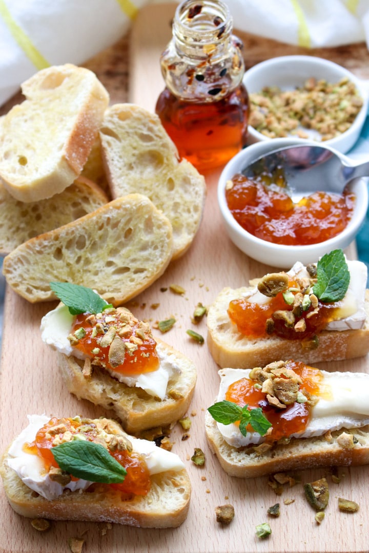 brie, apricot, pistachio crostini on a cutting board