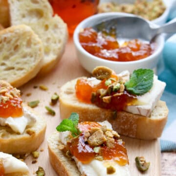 brie, apricot, pistachio crostini on a cutting board