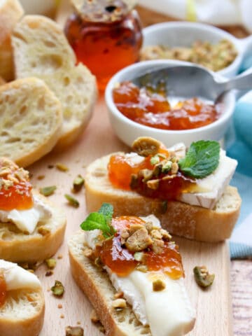 brie, apricot, pistachio crostini on a cutting board