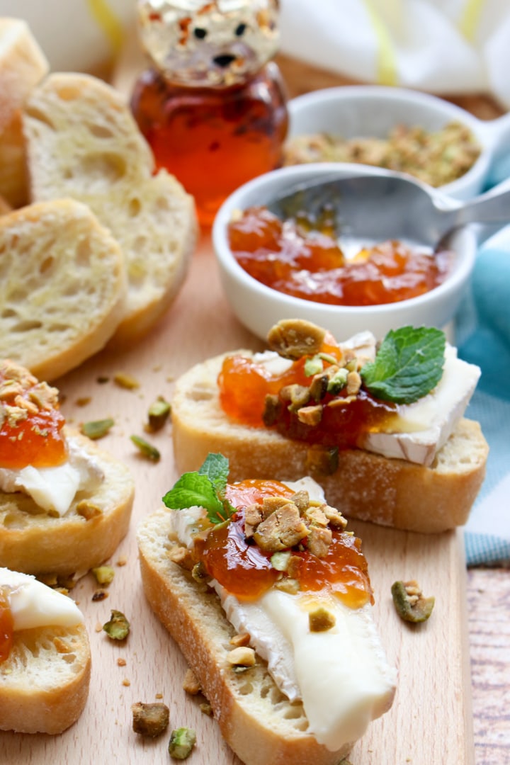 brie, apricot, pistacho crostini on a cutting board