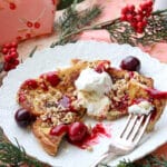 Lacy white plate with a slice of eggnog french toast and cranberry syrup