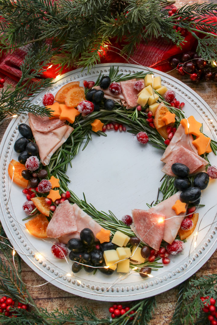 Deli meats and cheeses made into a charcuterie wreath with twinkling lights